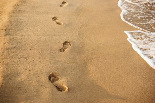 Children footprints in the sand. Human footprints leading away from the viewer. A row of footprints in the sand on a beach in the summertime. Summer Vacation