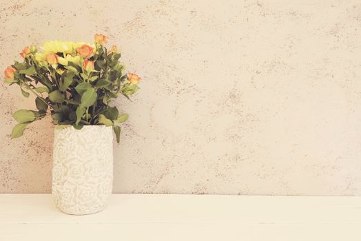 Vase of flowers. Rustic vase with orange roses and yellow chrysanthemums. White background, empty place, copy space. Vintage tinted