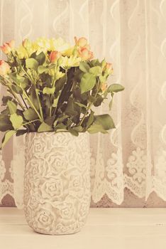 Vase of flowers. Rustic vase with orange roses and yellow chrysanthemums. White background, empty place, copy space. Vintage tinted