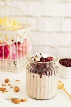 Overnight Chia Pudding With Chia Seeds, Oats, Pomegranate And Coconut Chips. Healthy Breakfast Concept. Bright Brick Wall Background. Yellow Roses in a Cage. Healthy Lifestyle Concept. Copy Space