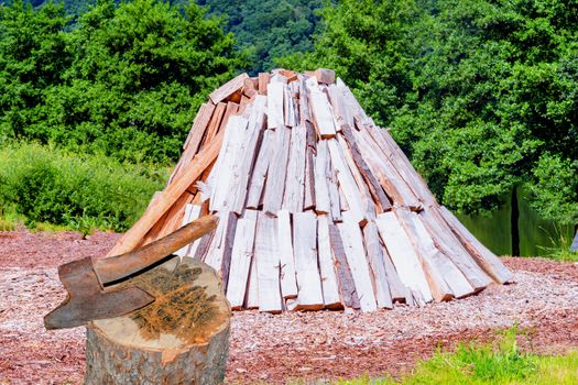 Conical stacked logs, firewood storage for the winter. In the foreground a hack wood with ax.
