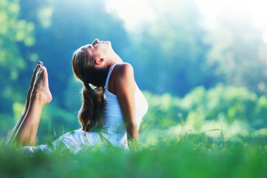 Young woman doing yoga exercise in green park