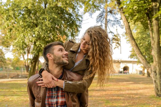 Handsome man carrying his beautiful girlfriend on his back