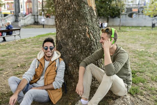 Two friends relaxing under the tree in the public park