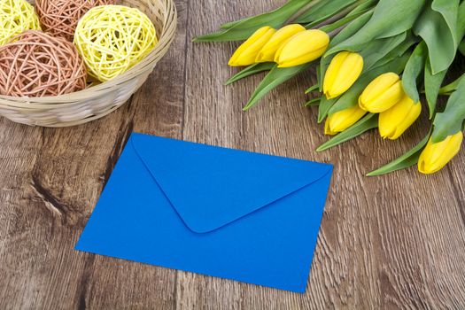 Blue envelope with tulips on a wooden table