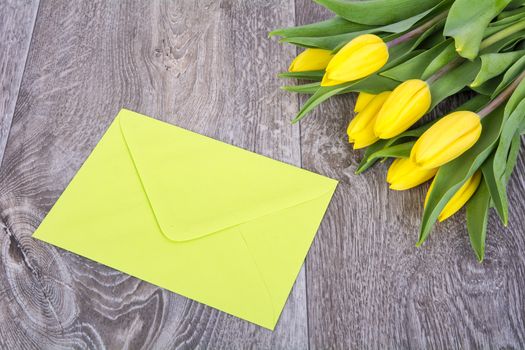 Green envelope with tulips on a wooden table