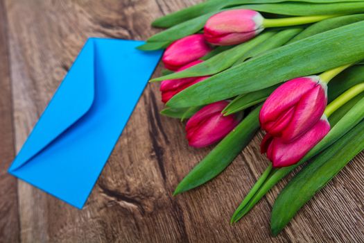 Blue envelope with tulips on a wooden table