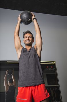 Man holding a small black weighted ball over his head