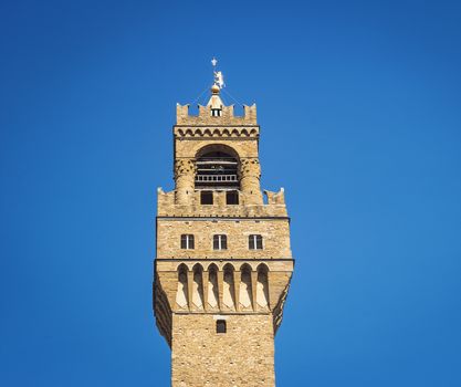 Detail of the bell tower of Palazzo Vecchio in Florence with the large windvane shaped like a heraldic lion holding the pole surmounted by the Florentine lily