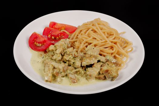 Spaghetti with tempeh and herb sauce on a black background