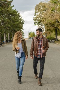 Attractive couple is refreshing with juice while having a nice time in the city park