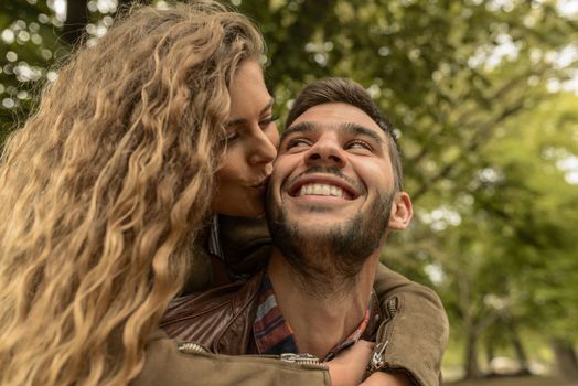 Attractive woman kissing her boyfriend in the public park