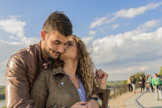 Attractive woman kissing her boyfriend under the bright blue sky