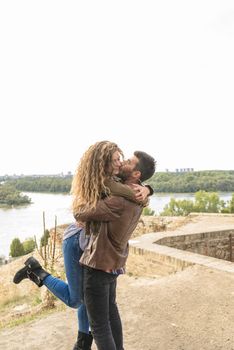 Attractive long haired girl is hugging his boyfriend while he is kissing her