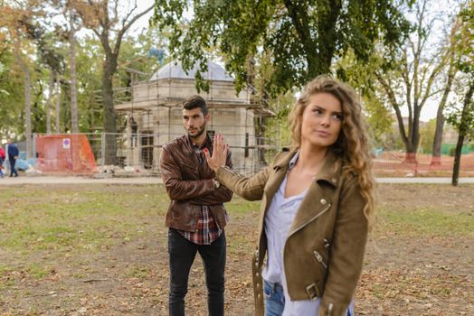 Beautiful long haired woman feeling disappointed and ignoring his boyfriend while he is trying to solve relationship problems