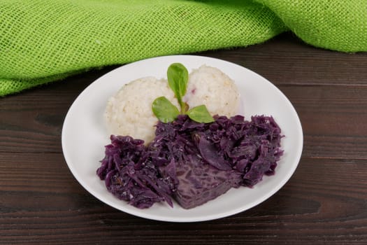 Tempeh with red cabbage and sorghum on a wooden table