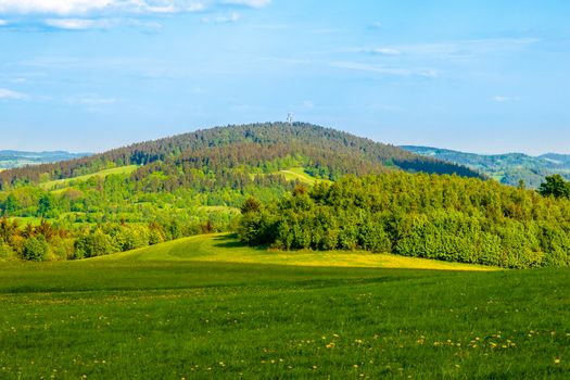 Green hill in the middle of sunny spring landscape. Javornik Mountain near Liberec, Czech Republic.