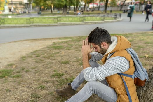 Displeased youngster is praying to the God in the city park