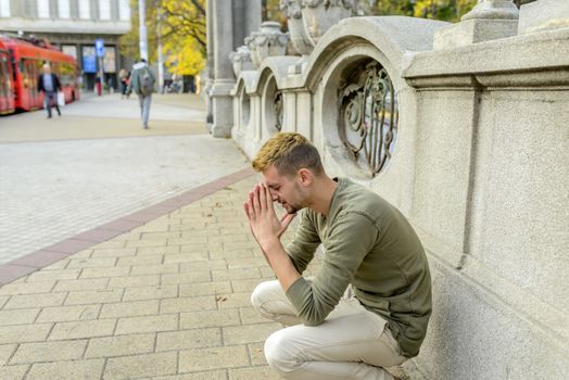 Stressed man is praying to the God and hoping for better times to come