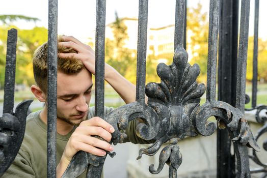 Young handsome man with problems near the gate