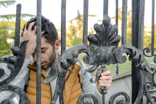 Young handsome man with problems near the gate