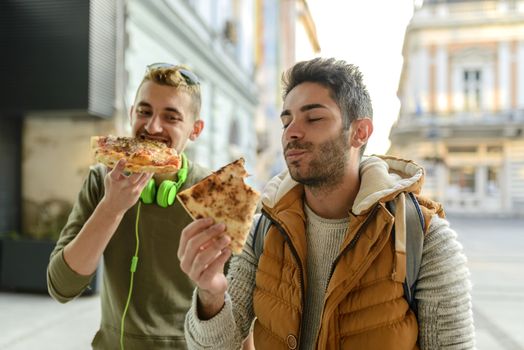 Two young hipsters are enjoying a snack in the city street