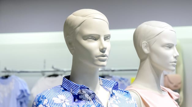 Closeup plastic mannequin heads against blurred shop background. Shallow focus.Man and woman mannequins.