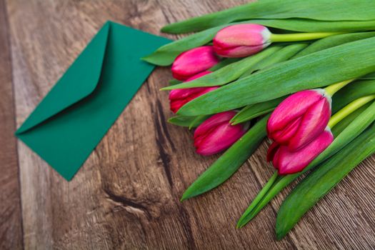 Pink envelope with tulips on a wooden table