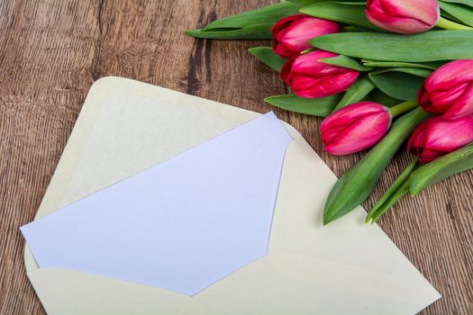 Pink envelope with tulips on a wooden table