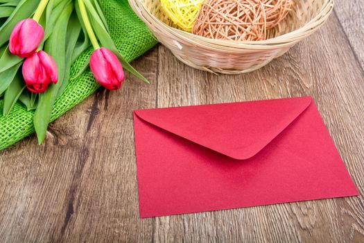 Pink envelope with tulips on a wooden table