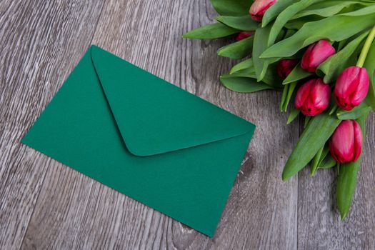 Pink envelope with tulips on a wooden table