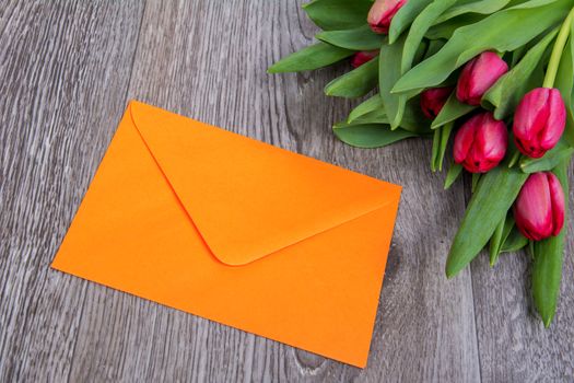 Pink envelope with tulips on a wooden table