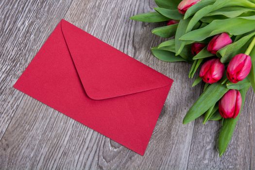 Pink envelope with tulips on a wooden table