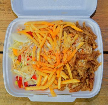 Fast food: kebabs, fries and fresh salad in the tray on the table. Unhealthy food concept. 