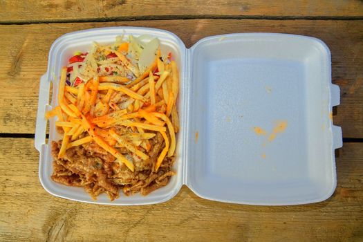 Lunch Box: kebabs, fries and fresh salad in tray. Close-up on the table. Unhealthy food concept. 