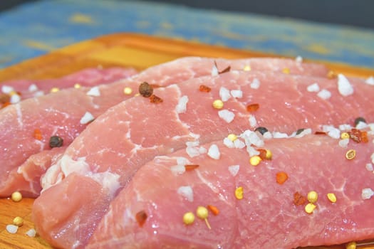 Pork chops with spices on a cutting board.Slices of pork steaks. Pork chops ready to fry. 