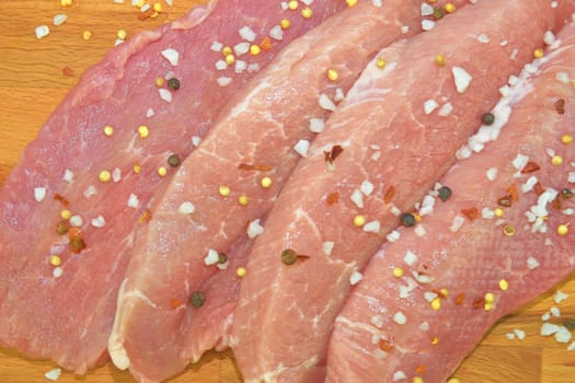 Pork chops with spices on a cutting board. Slices of pork steaks. Pork chops ready to fry. Selective focus. 