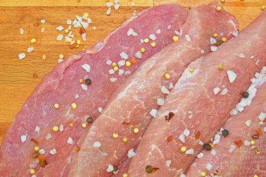 Raw pork loin chops on a cutting board with spices. Pork chops with spices on a cutting board. Slices of pork steaks. Pork chops ready to fry. Selective focus. 