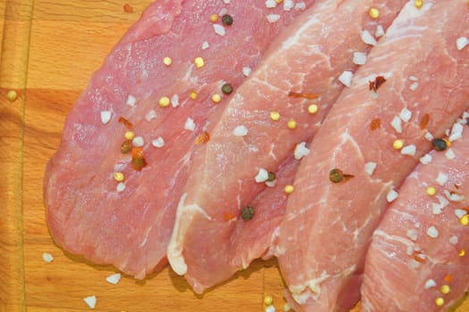 Pork chops with spices on a cutting board. Slices of pork steaks. Pork chops ready to fry. Selective focus. 