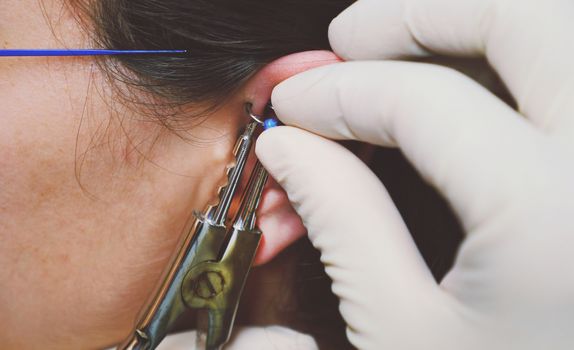 Close up detail shot of using equipment for ear piercing after using numbing cream