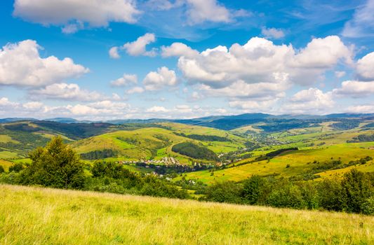 village in the valley of Carpathian mountains. lovely countryside scenery in early autumn with clouds on a blue sky over the distant ridge