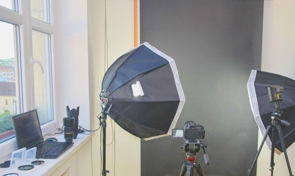 Empty photo studio with lighting equipment. Professional camera, lenses and filters for photographer.