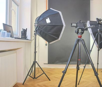 Empty photo studio with lighting equipment. Professional camera, lenses and filters for photographer.