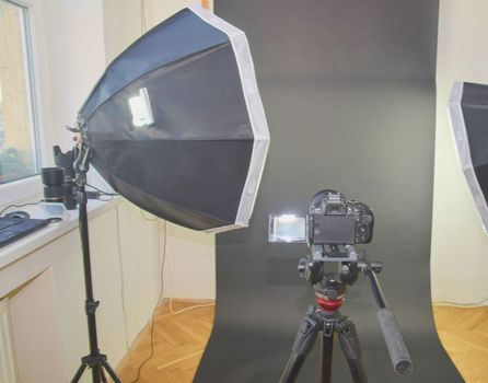 Empty photo studio with lighting equipment. Professional camera, lenses and filters for photographer.