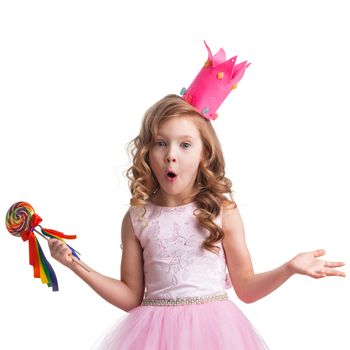 Surprised little candy princess girl in crown holding big lollipop and shrug shoulders