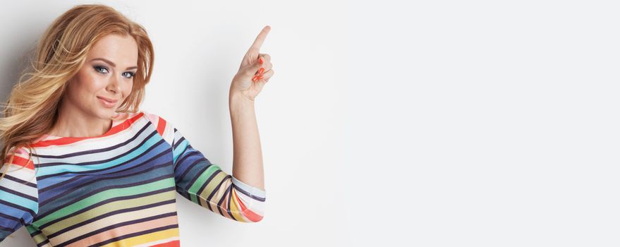 Portrait of cute girl colorful rainbow blouse pointing to the side to empty copy space