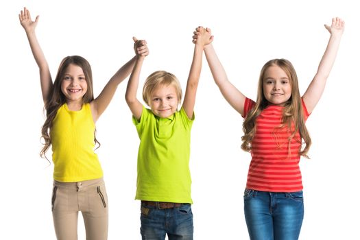 Happy smiling three children in colorful clothes holding raised hands isolated on white background