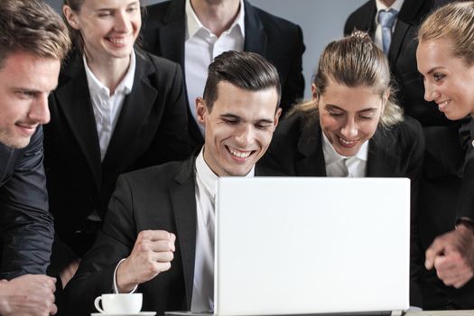 Happy business team look together at one laptop, copy space