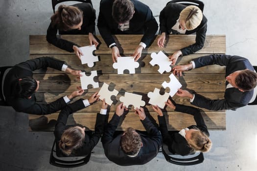 Business people and puzzle on wooden table, teamwork concept