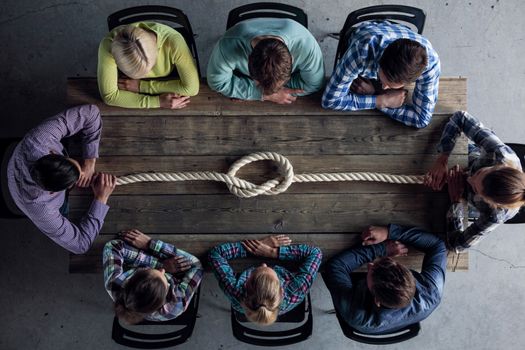 Problem solution concept, team of people in casual clothes sitting around the table with rope node